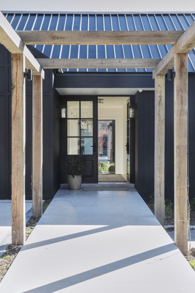 Modern farmhouse entry with timber pergola and black exterior