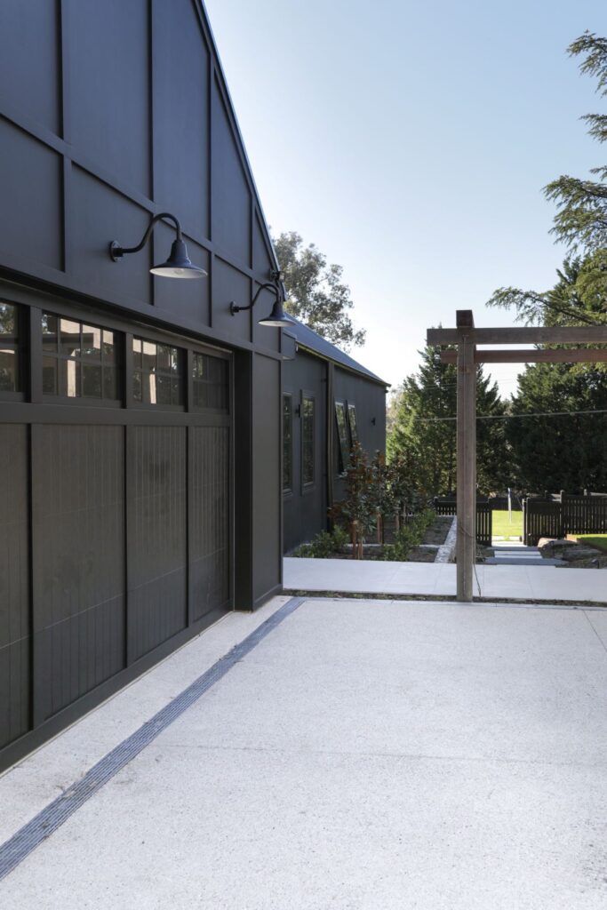 Modern farmhouse exterior with black cladding and timber pergola