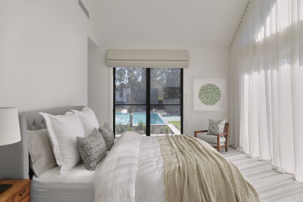 Light filled bedroom with sheer curtains and pool view