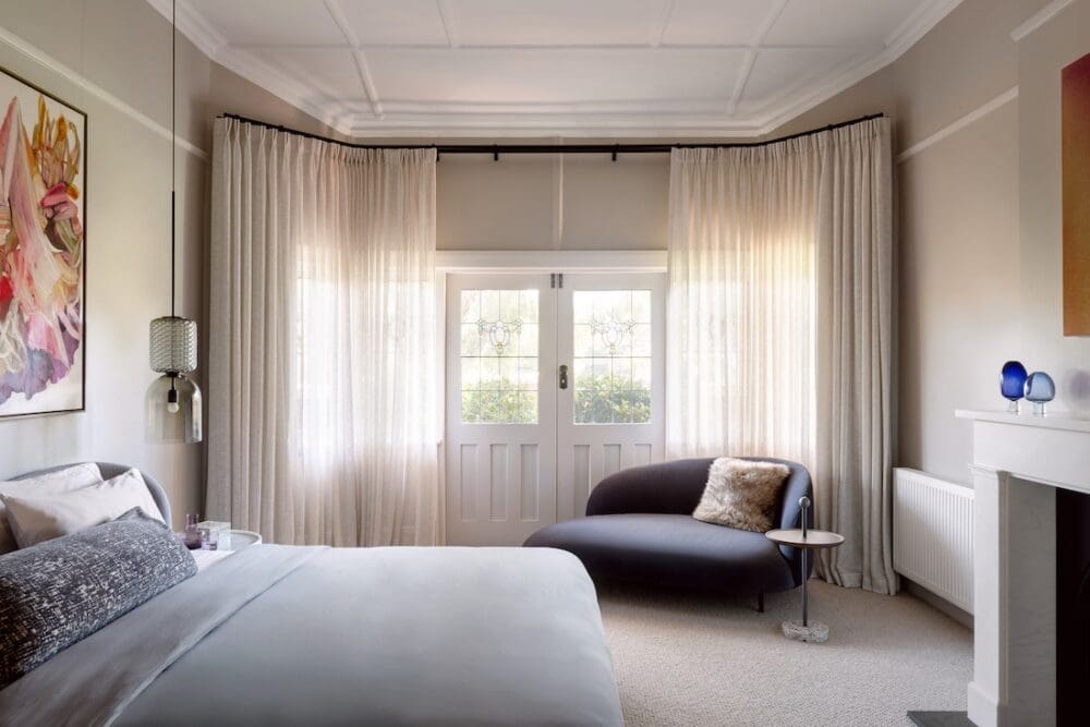 Beautiful bedroom with curved curtain track around bay windows and door