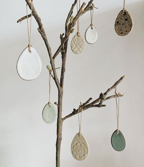 Handmade ceramic ornaments hanging from decorative branch