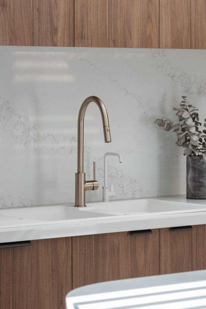 Walnut kitchen joinery with white stone splashback and tap