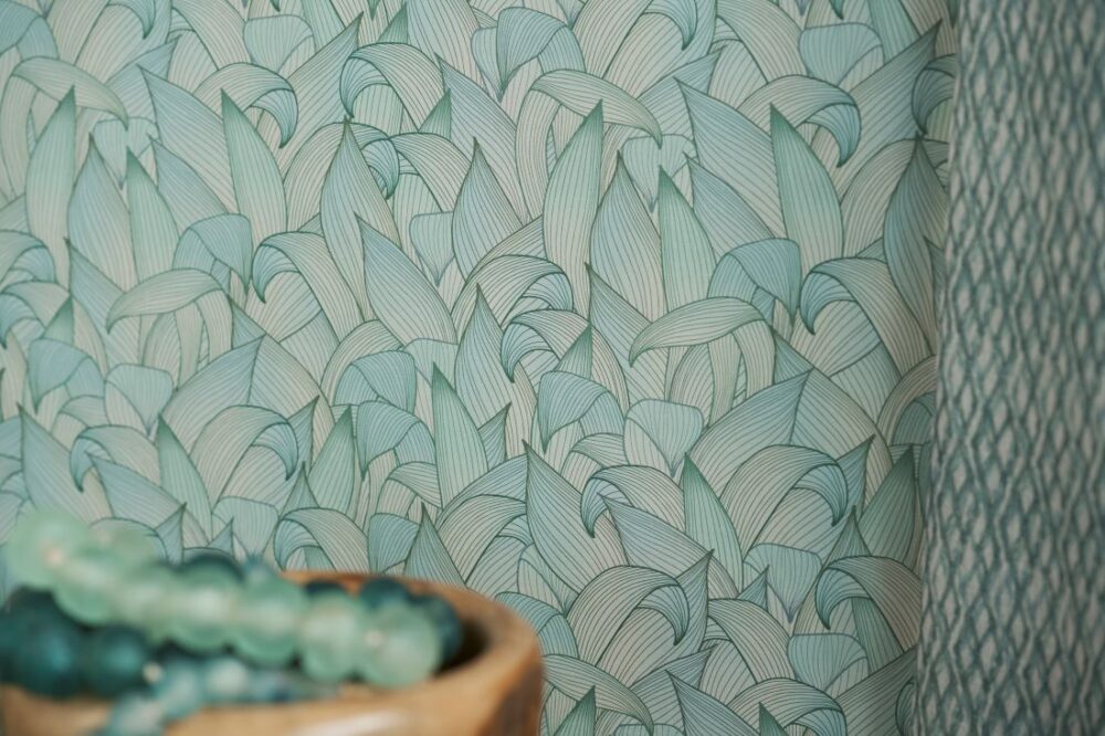 Morning Sunshine - Shore wallpaper featuring a soft teal leaf pattern, complemented by a collection of teal beads in a wooden bowl.