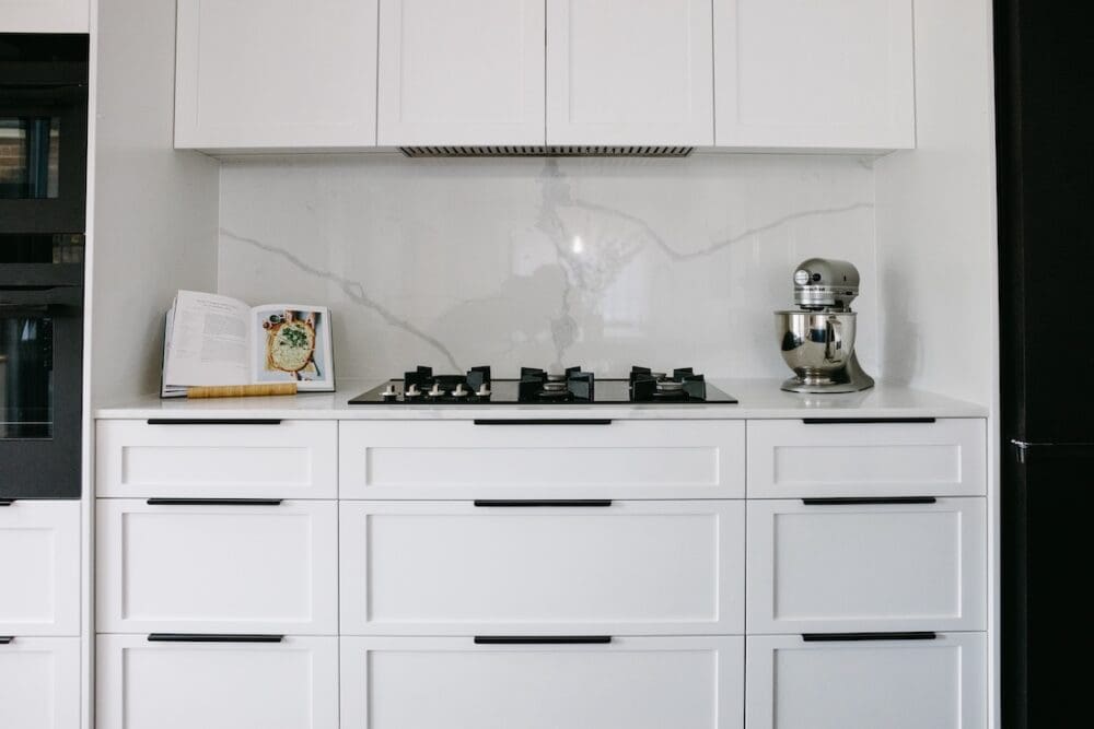 Cooktop in Hamptons style kitchen with white shaker style joinery and black handles