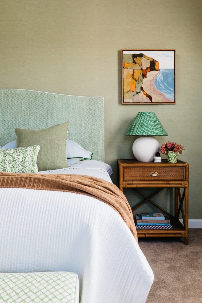 Green bedroom with green upholstered bedhead and cane side table