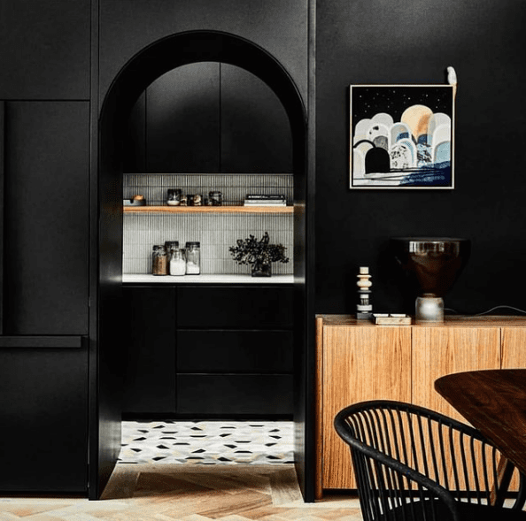 Black dining room wall with curved arch doorway